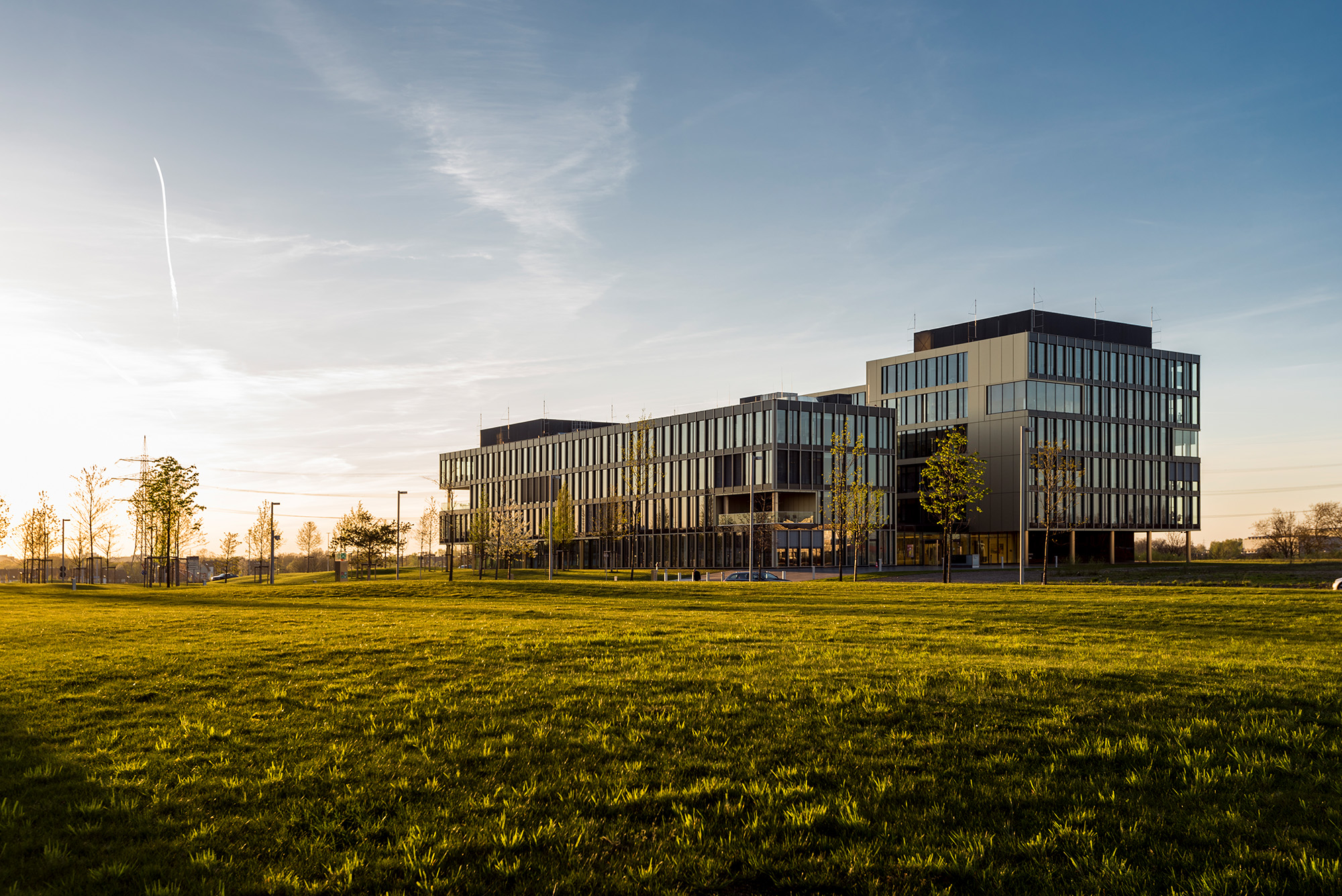 Der thyssenkrupp Campus in Essen mit seinen markanten, modernen Fronten und dem modernen Baustil eines zukunftsweisenden Offices. Im Vordergrund ist begrünte Fläche.