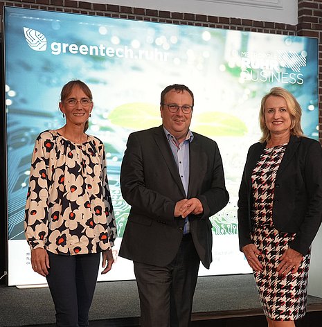 Four people stand in front of a Greentech.Ruhr poster: Christina Zollmarsch, NRW Environment Minister Krischer, Prof. Dr. Julia Frohne and Alisa Schuler.