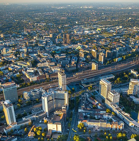 Abgebildet ist das Ruhrgebiet von oben. Zu sehen sind viele moderne Bürogebäude und die Autobahn innerhalb der Stadt.