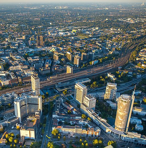 Pictured is the Ruhr area from above. You can see many modern office buildings and the highway inside the city.