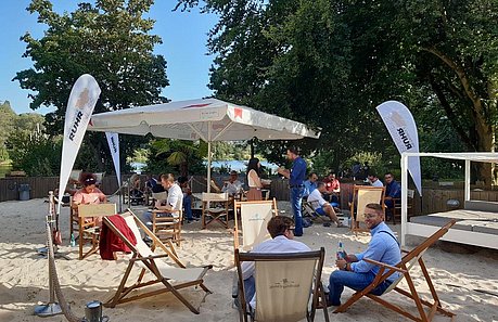 Ein Greentech.Ruhr Netzwerktreffen in entspannter Beach-Atmosphäre, bei dem Netzwerkpartner auf Strandstühlen sitzen und zu Fachthemen Austausch betreiben.