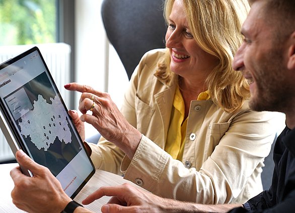Prof. Dr. Julia Frohne und Hendrik Weyers aus dem Projektteam klicken auf einem Tablet durch die neue Website der Business Metropole Ruhr. Abgebildet ist ein Tablet mit dem neuen Kartentool auf der Website.