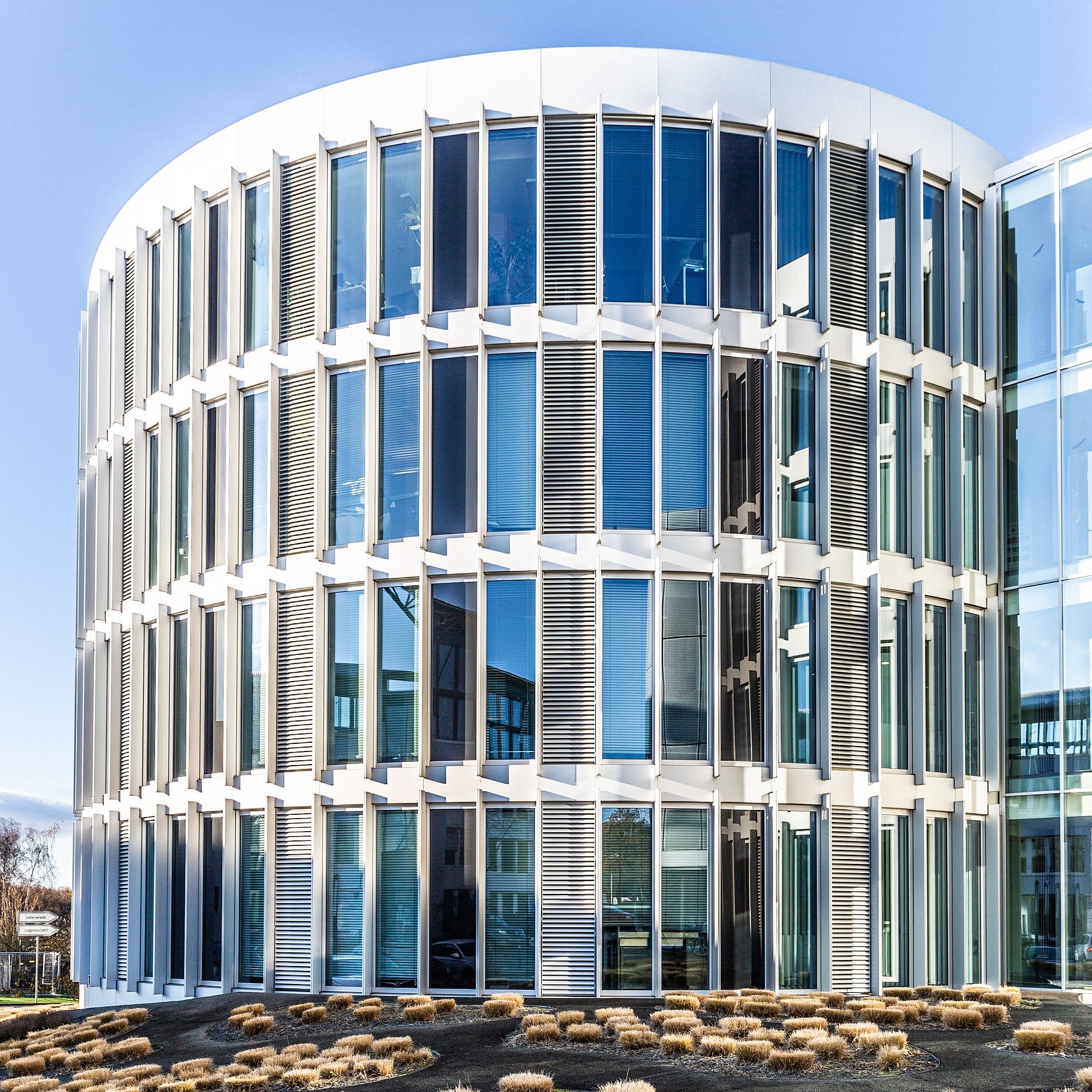 Eines der Innovationszentren Ruhr im Ruhrgebiet von vorne, zu sehen sind Pflanzen im Vordergrund mit dem runden, modern anmutenden Glasgebäude im Hintergrund
